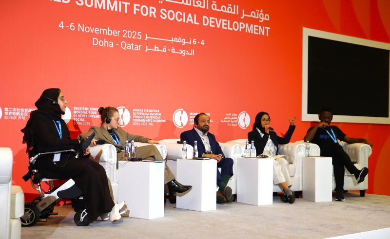 A speaker presenting at a podium while five panelists sit on stage during the Second World Summit for Social Development in Doha, Qatar.