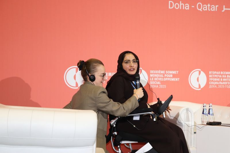 Polly and Fatma seated on stage in conversation, with Polly  holding a microphone, at the Second World Summit for Social Development in Doha, Qatar.
