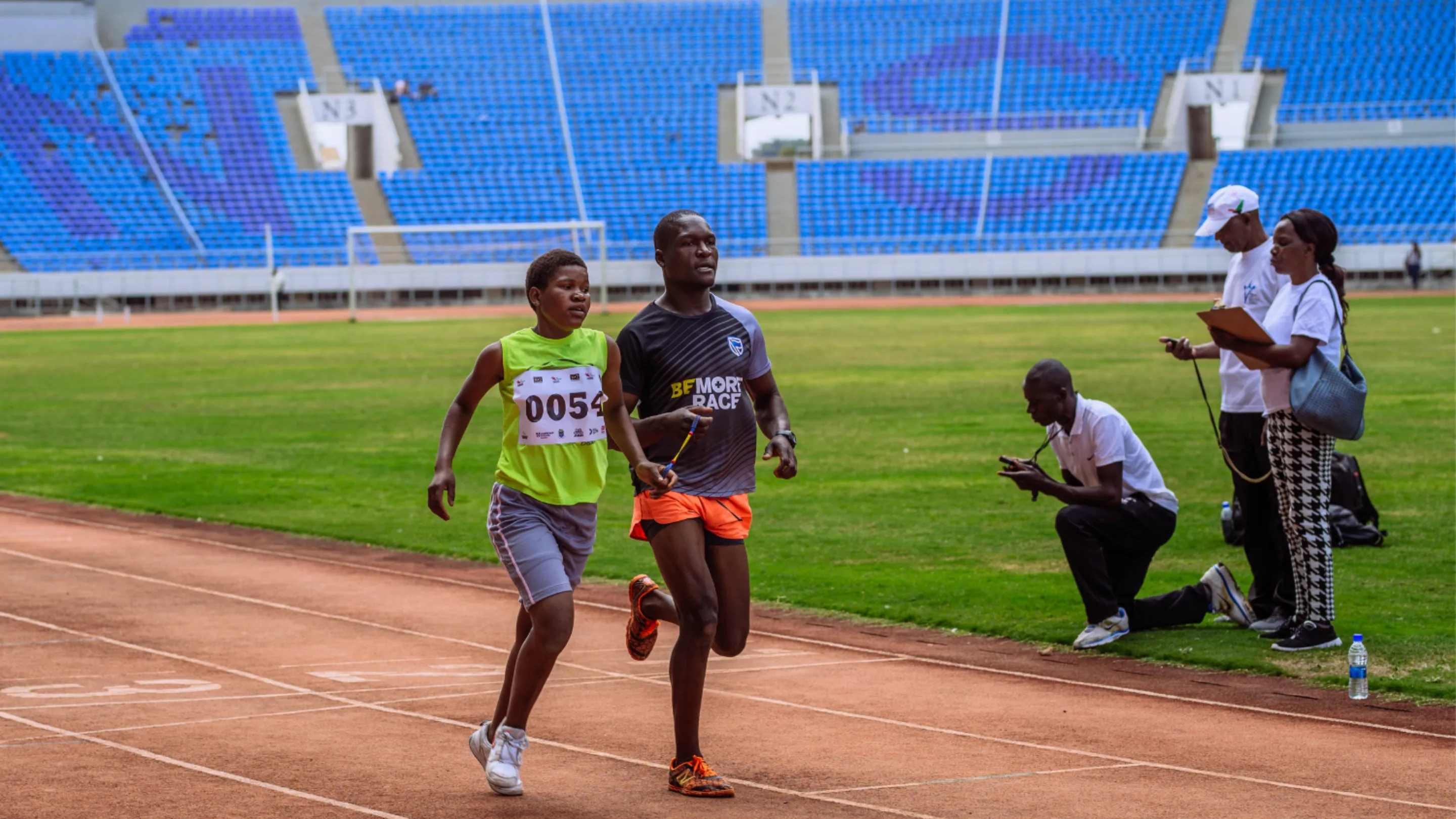 Two people running on a running track. One is a sighted support runner