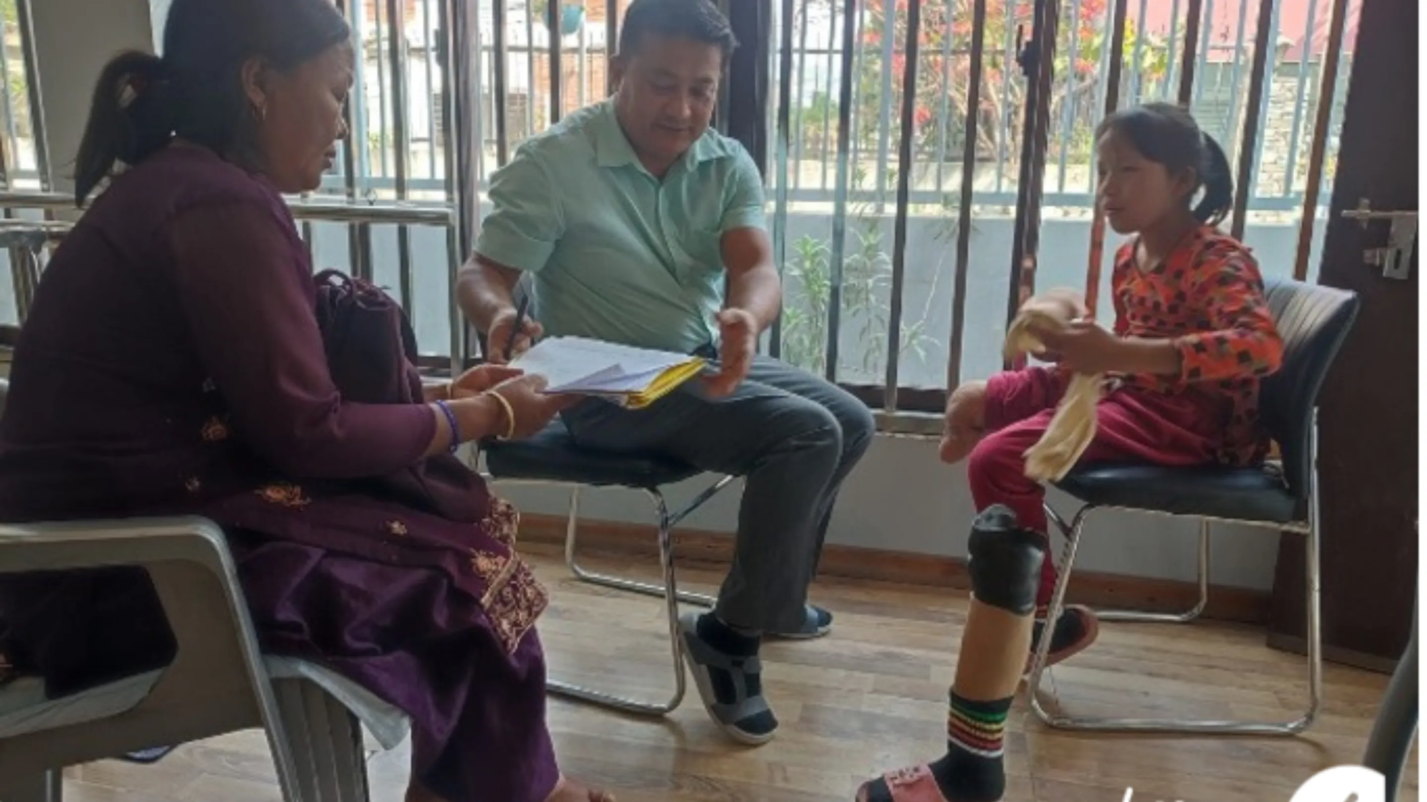 3 people sat in chairs talking.