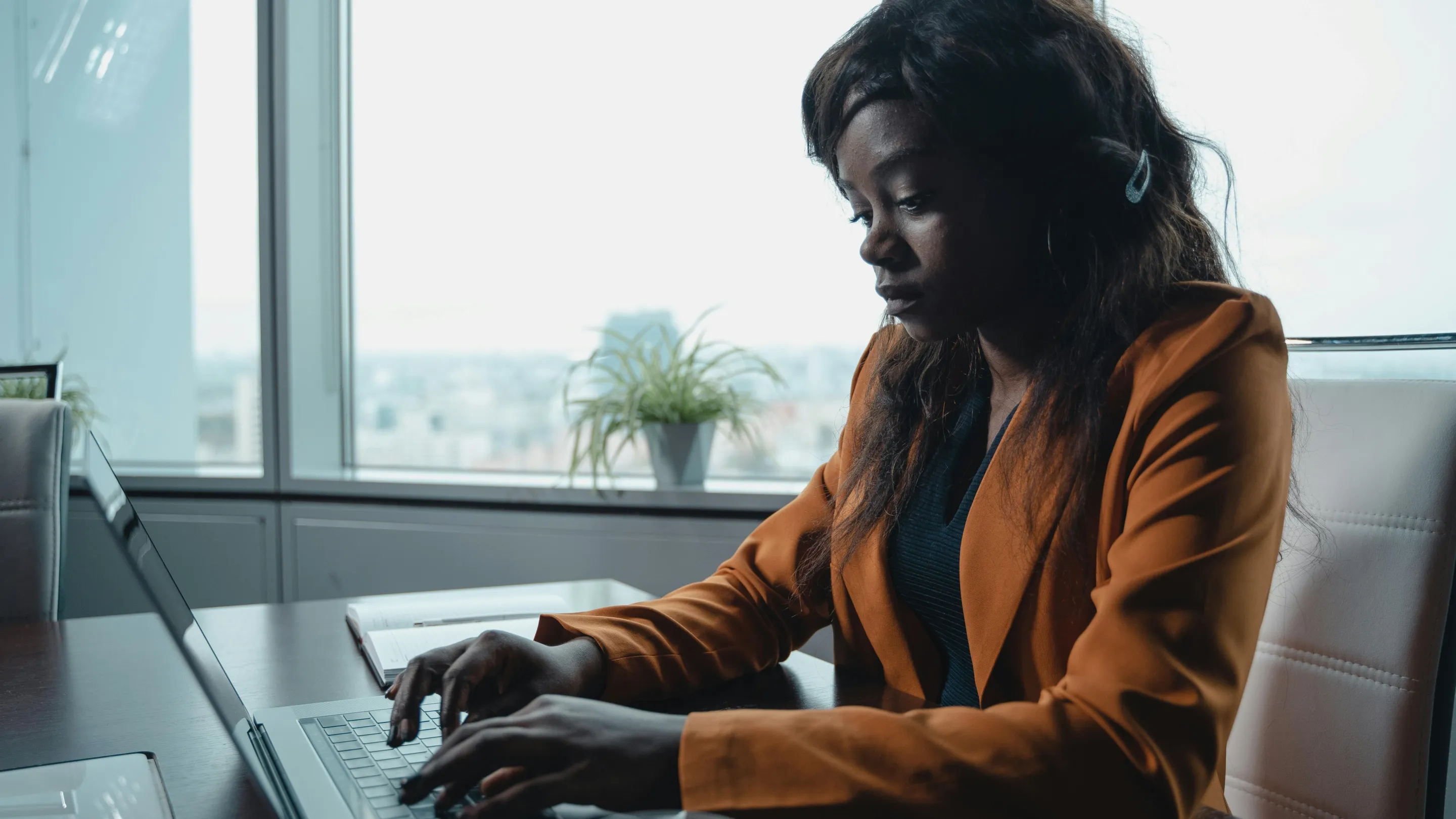 A Woman in an Orange Blazer Typing on a Laptop