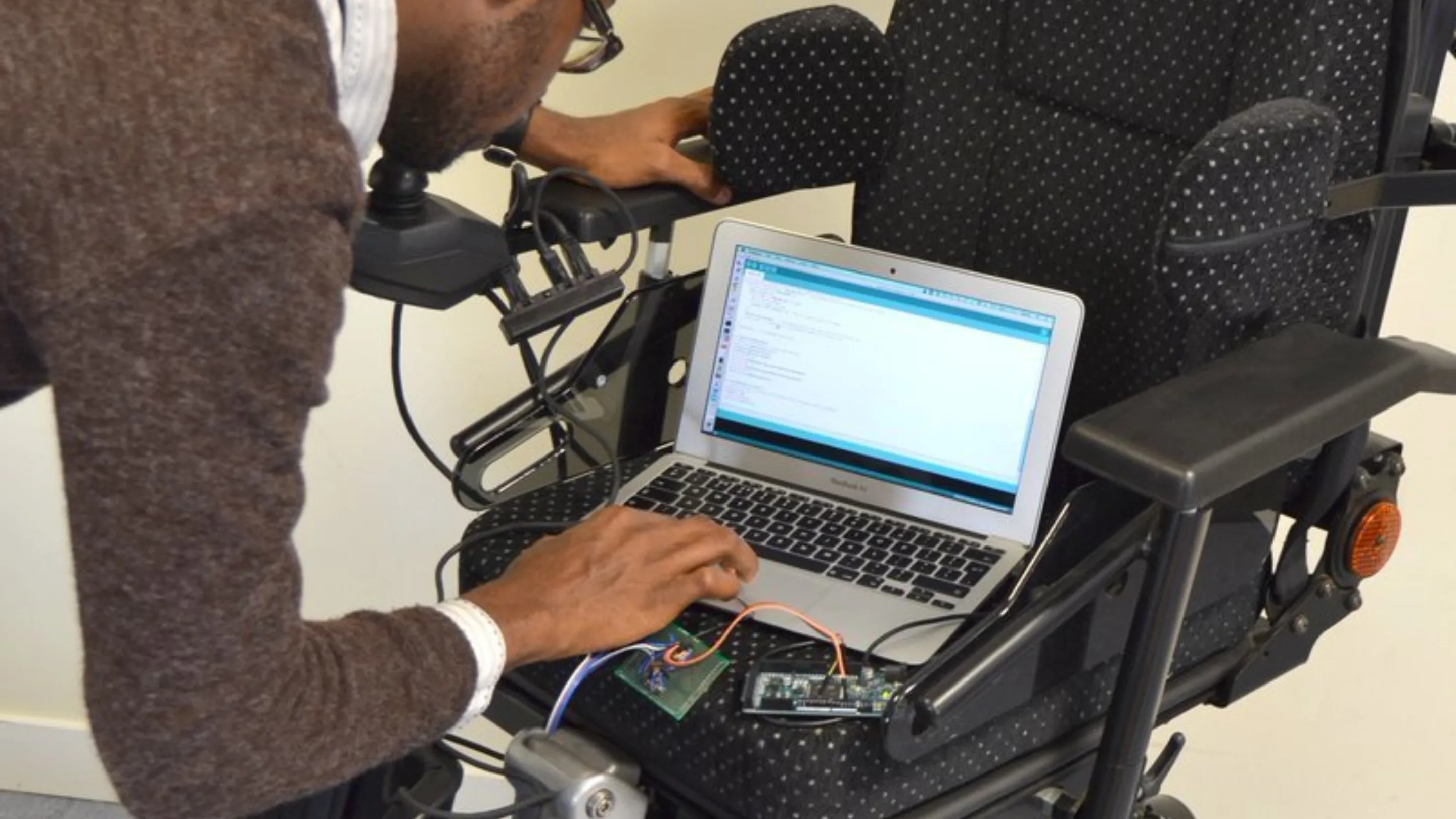 Man using a latop to operate a wheelchair