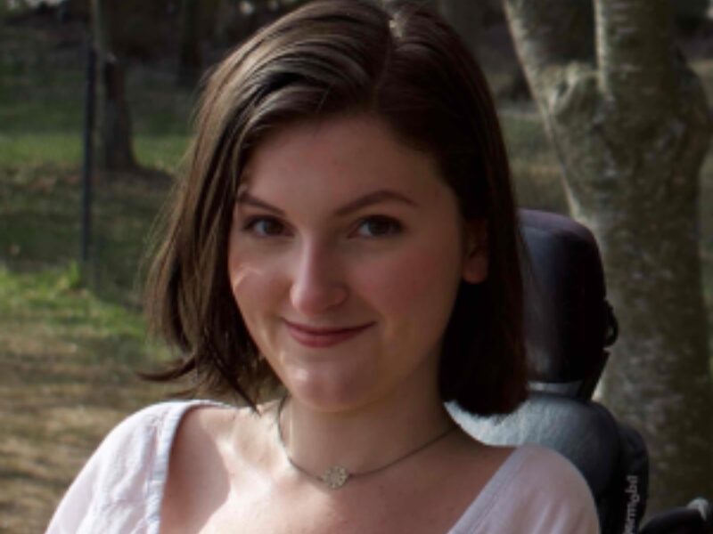 A photograph of Anna, a white woman with short dark hair who is smiling towards the camera