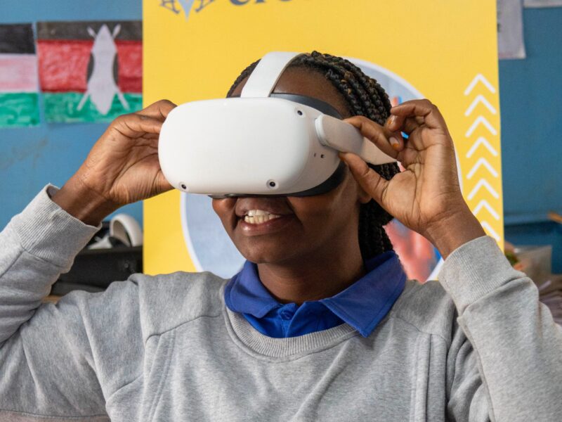 A person wearing a virtual reality headset adjusts it with their hands.