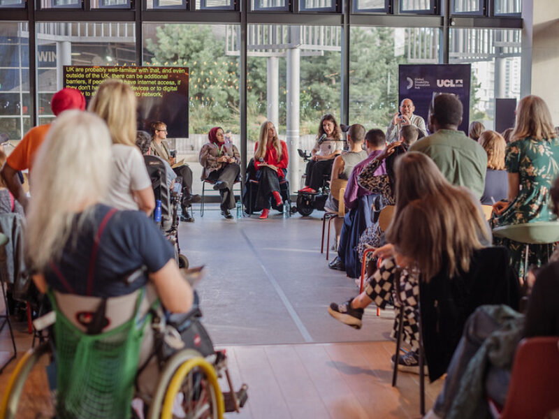 An image of the audience listening to speakers at the 10 year celebratory event - with three female speakers on a flat stage