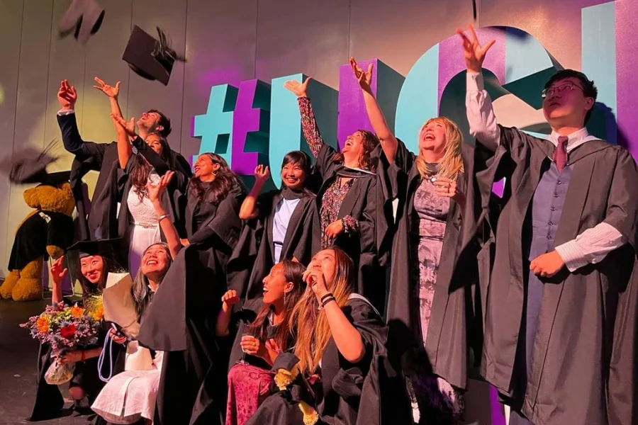 Graduation photo of MSc cohort in gowns, throwing hats into the air