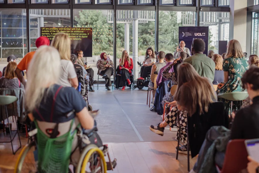 An image of the audience listening to speakers at the 10 year celebratory event - with three female speakers on a flat stage